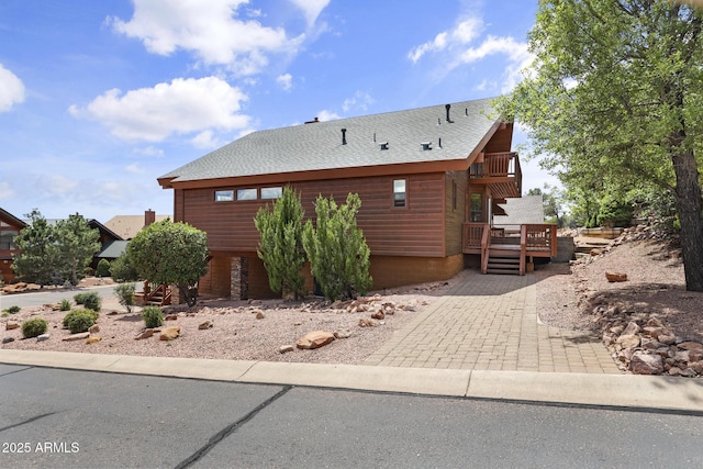 view of property exterior with roof with shingles and a deck