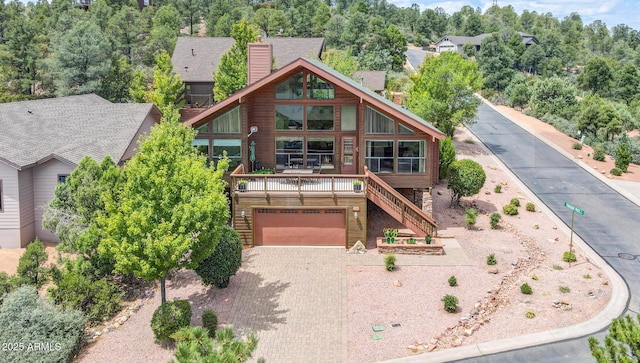 view of front of house with an attached garage, stairway, a chimney, a deck, and driveway