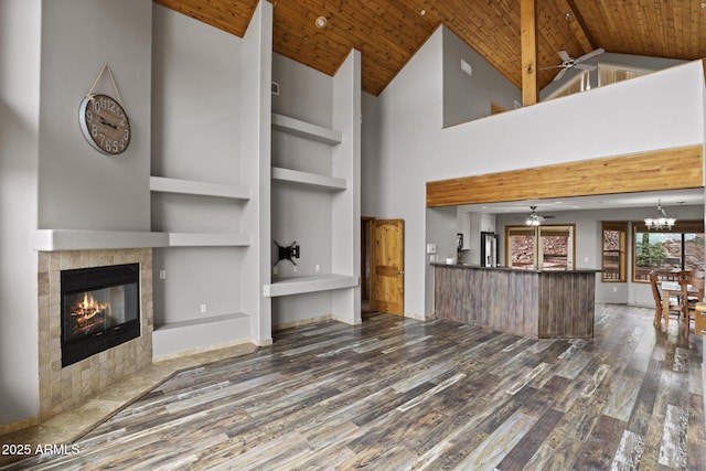 unfurnished living room with wood finished floors, wood ceiling, built in shelves, and ceiling fan with notable chandelier