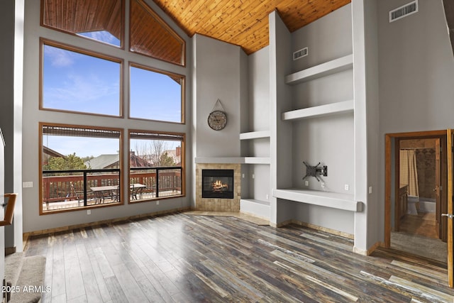 unfurnished living room featuring wooden ceiling, built in shelves, wood finished floors, and visible vents