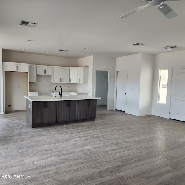 22232 W Skinner Rd, Wittmann, AZ 85361 - kitchen featuring ceiling fan, light hardwood / wood-style floors, a kitchen island with sink, and white cabinets