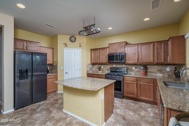 kitchen with black fridge with ice dispenser, sink, stainless steel gas stove, a kitchen island, and decorative backsplash