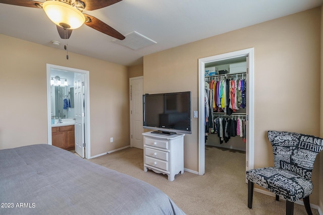 carpeted bedroom featuring ceiling fan, ensuite bathroom, a spacious closet, and sink