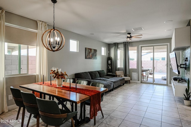 tiled dining room with ceiling fan with notable chandelier