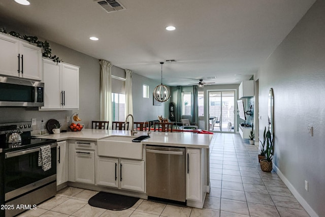 kitchen with white cabinetry, sink, stainless steel appliances, and kitchen peninsula