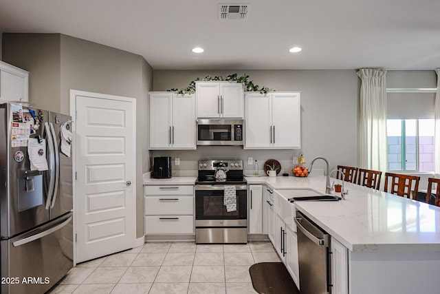 kitchen featuring sink, white cabinetry, light tile patterned floors, kitchen peninsula, and stainless steel appliances