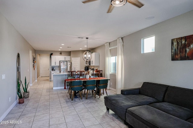 tiled dining room with ceiling fan with notable chandelier