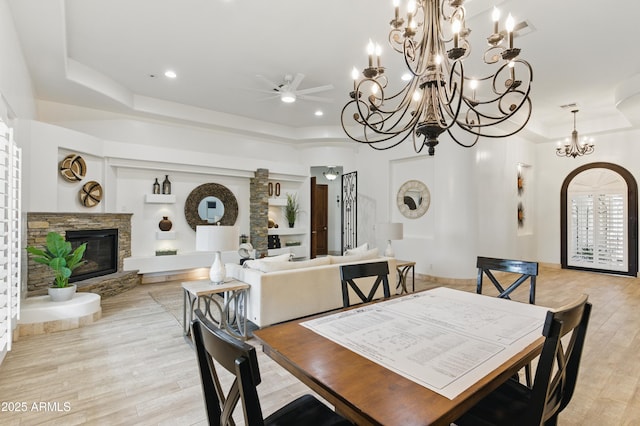 6146 E Dixileta Dr, Cave Creek, AZ 85331 - dining space with a raised ceiling, ceiling fan with notable chandelier, light wood finished floors, and a stone fireplace