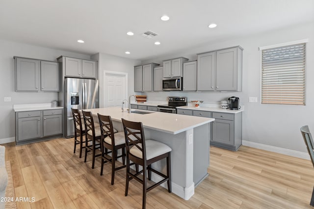 kitchen with a kitchen breakfast bar, sink, light hardwood / wood-style flooring, and stainless steel appliances