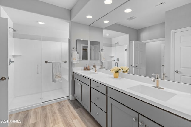 bathroom with wood-type flooring, a shower with door, and vanity