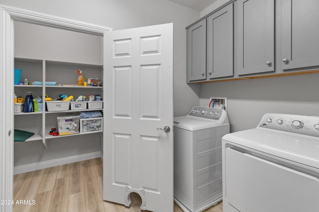 laundry room featuring separate washer and dryer, cabinets, and light wood-type flooring