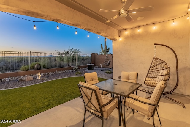 patio terrace at dusk with a yard and ceiling fan