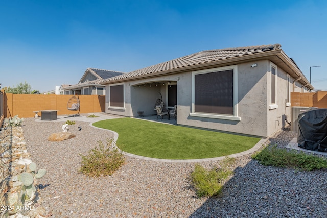 back of property with a lawn and a patio area