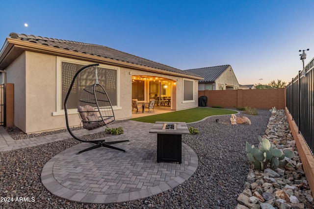 back house at dusk featuring a patio and an outdoor fire pit