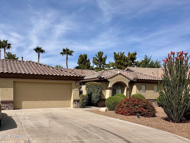 mediterranean / spanish house featuring concrete driveway, a tiled roof, a garage, and stucco siding