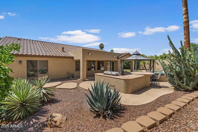 rear view of house featuring a tiled roof, a gazebo, a patio area, and stucco siding