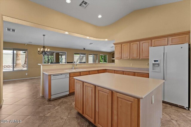 kitchen with visible vents, a peninsula, white appliances, light countertops, and a sink