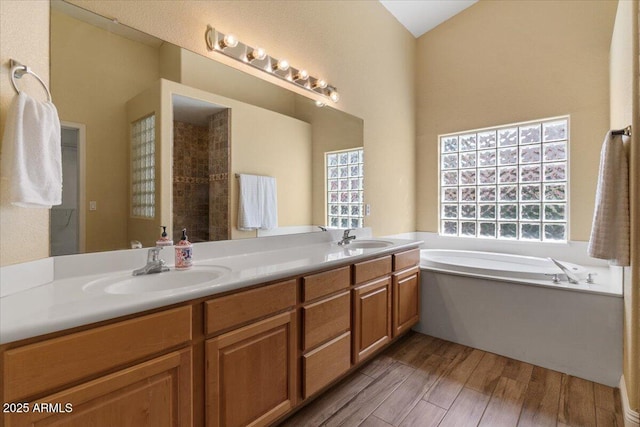 full bath featuring a garden tub, a sink, wood finished floors, and double vanity