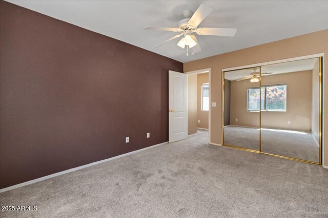 unfurnished bedroom with carpet floors, baseboards, ceiling fan, and a closet
