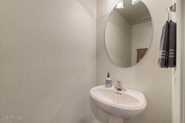 bathroom with visible vents, a sink, and a textured wall