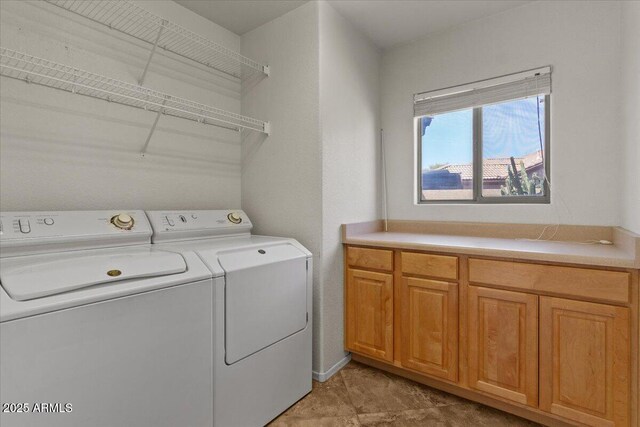 clothes washing area featuring washing machine and clothes dryer and cabinet space