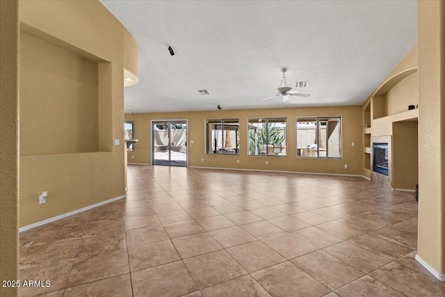 unfurnished living room with a ceiling fan, baseboards, visible vents, and a wealth of natural light