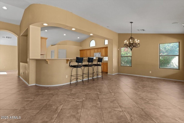 kitchen with a peninsula, lofted ceiling, a breakfast bar, open floor plan, and a notable chandelier