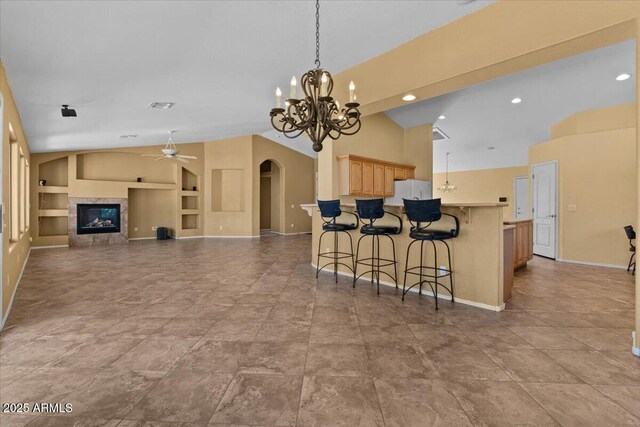 kitchen featuring a kitchen breakfast bar, built in features, arched walkways, baseboards, and ceiling fan with notable chandelier