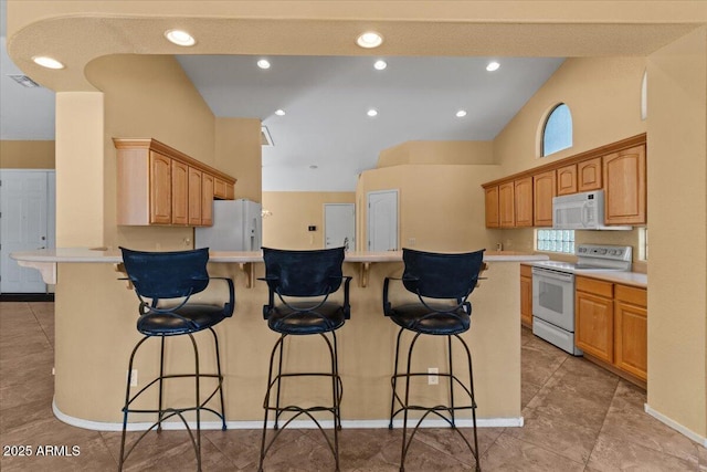 kitchen with a kitchen breakfast bar, visible vents, light countertops, a peninsula, and white appliances