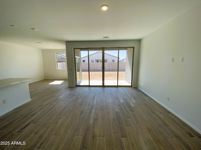 unfurnished room featuring visible vents, baseboards, and dark wood finished floors