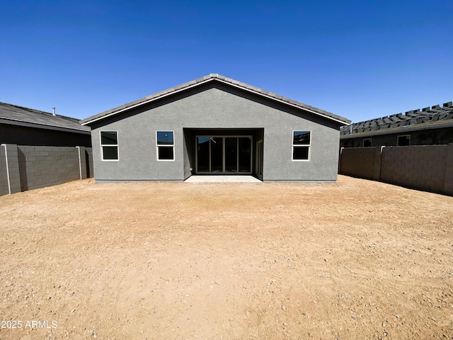 back of house with a fenced backyard and stucco siding
