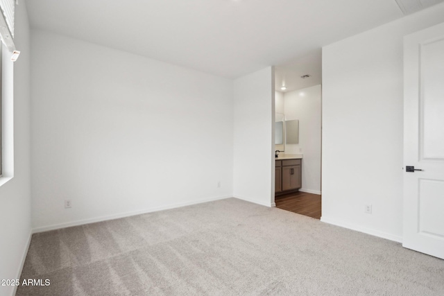 unfurnished bedroom with dark colored carpet, ensuite bath, visible vents, and baseboards
