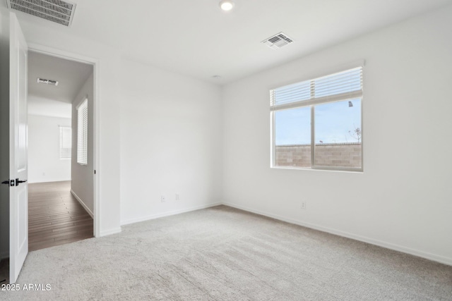 carpeted spare room featuring visible vents, baseboards, and a healthy amount of sunlight