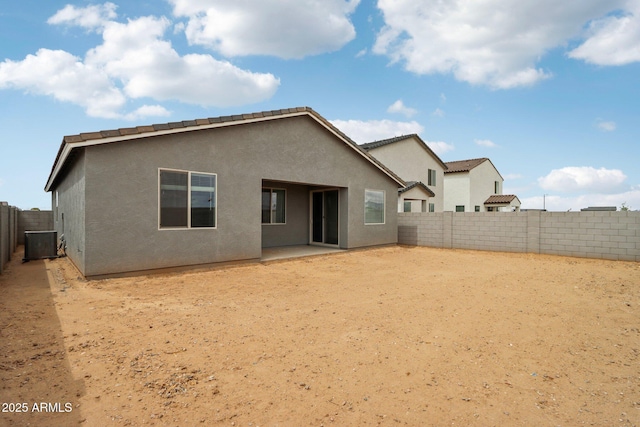 rear view of property with a fenced backyard, stucco siding, central AC unit, and a patio area