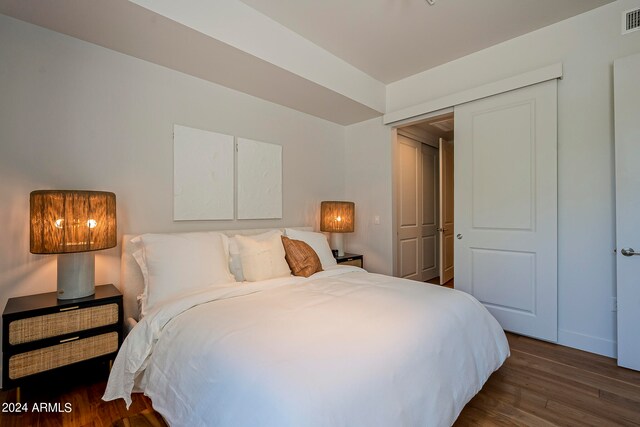 bedroom with dark hardwood / wood-style flooring and a closet