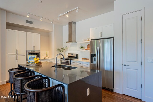 kitchen featuring wall chimney range hood, white cabinets, appliances with stainless steel finishes, and dark wood-type flooring