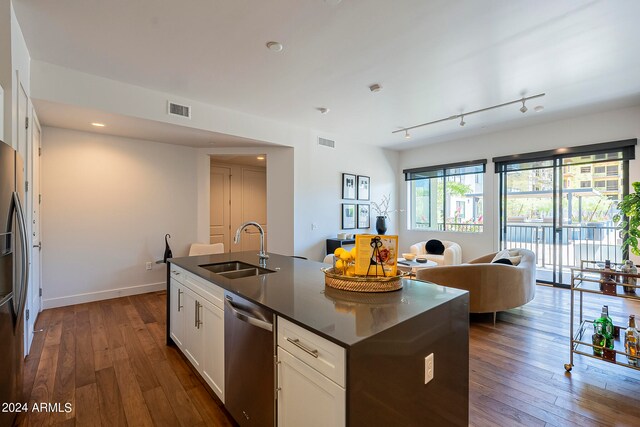 kitchen featuring dark hardwood / wood-style floors, sink, stainless steel dishwasher, track lighting, and white cabinetry