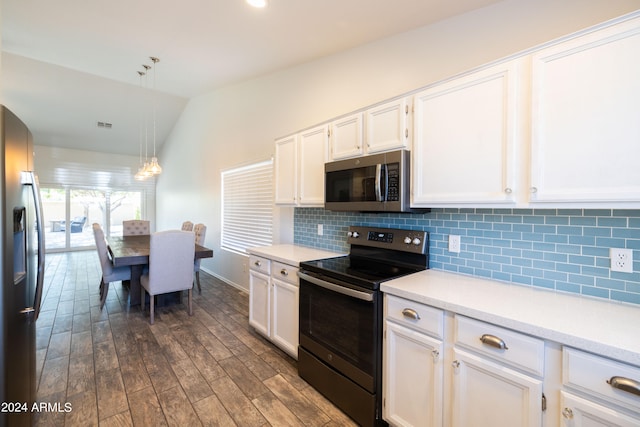 kitchen with appliances with stainless steel finishes, lofted ceiling, decorative light fixtures, white cabinets, and dark wood-type flooring