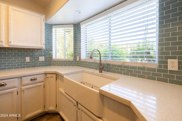 kitchen with dark wood-type flooring, light stone countertops, decorative backsplash, and sink