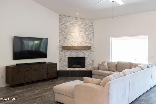 living room featuring ceiling fan, a stone fireplace, vaulted ceiling, and dark hardwood / wood-style flooring