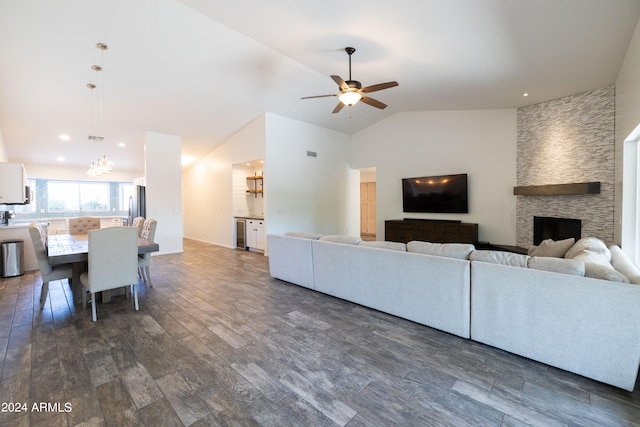 living room featuring ceiling fan, a stone fireplace, lofted ceiling, and dark hardwood / wood-style floors