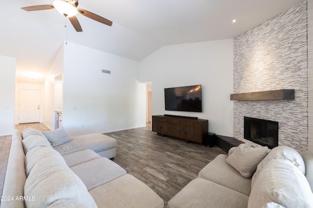 living room with vaulted ceiling, a stone fireplace, wood-type flooring, and ceiling fan