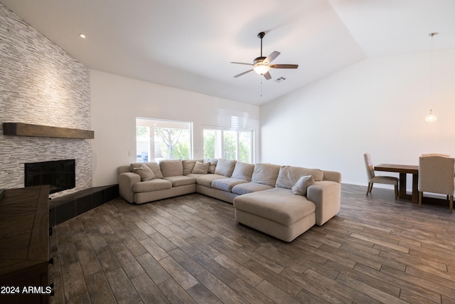 living room featuring a stone fireplace, lofted ceiling, dark hardwood / wood-style floors, and ceiling fan