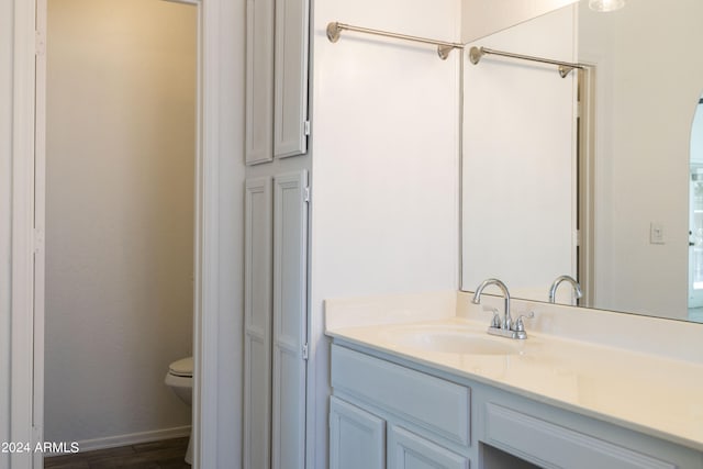 bathroom with vanity, toilet, and hardwood / wood-style floors