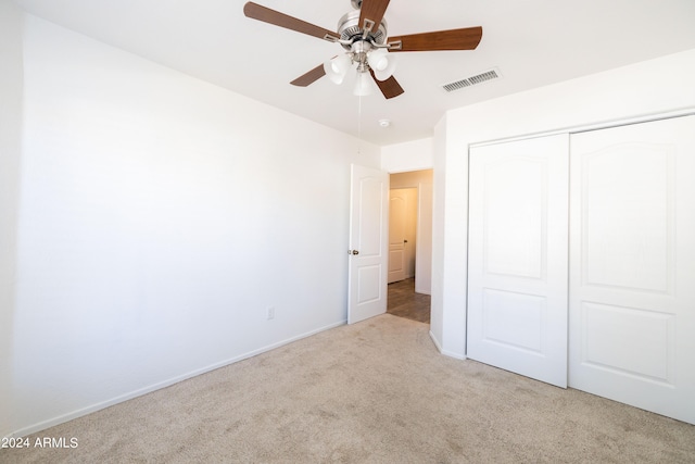 unfurnished bedroom featuring a closet, light colored carpet, and ceiling fan