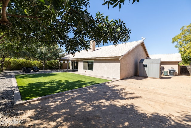 rear view of property featuring a shed and a lawn