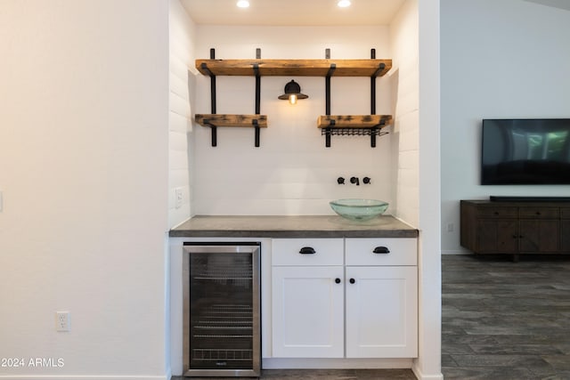 bar featuring white cabinets, dark wood-type flooring, and beverage cooler