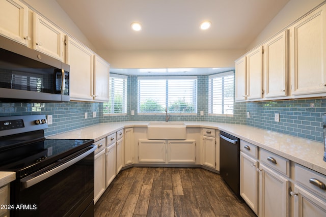 kitchen featuring tasteful backsplash, vaulted ceiling, dark wood-type flooring, sink, and stainless steel appliances