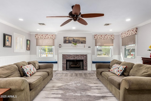 living room with ornamental molding, ceiling fan, a fireplace, and light hardwood / wood-style flooring