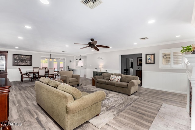 living room with crown molding, ceiling fan, and light hardwood / wood-style flooring